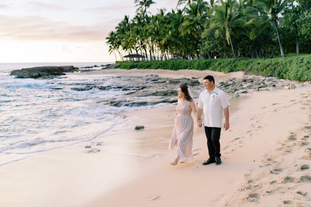 Bride is wearing a white wedding dress, the groom is wearing a white tuxedo. Classic Hawaiian wedding photography Oahu.