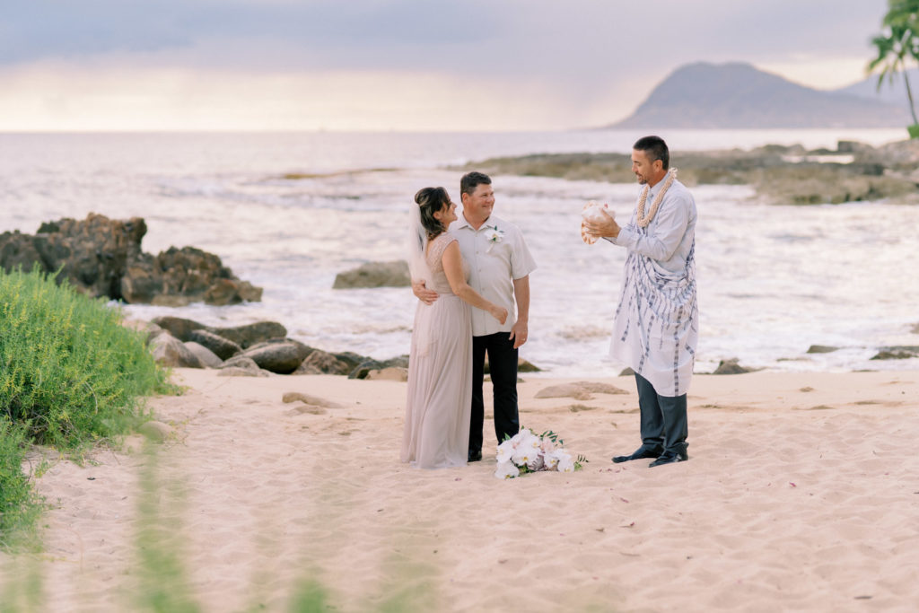 A wedding ceremony at the Four Seasons Resort in Oahu Hawaii. Wedding photographers love the simplicity of elopement weddings on the beach.