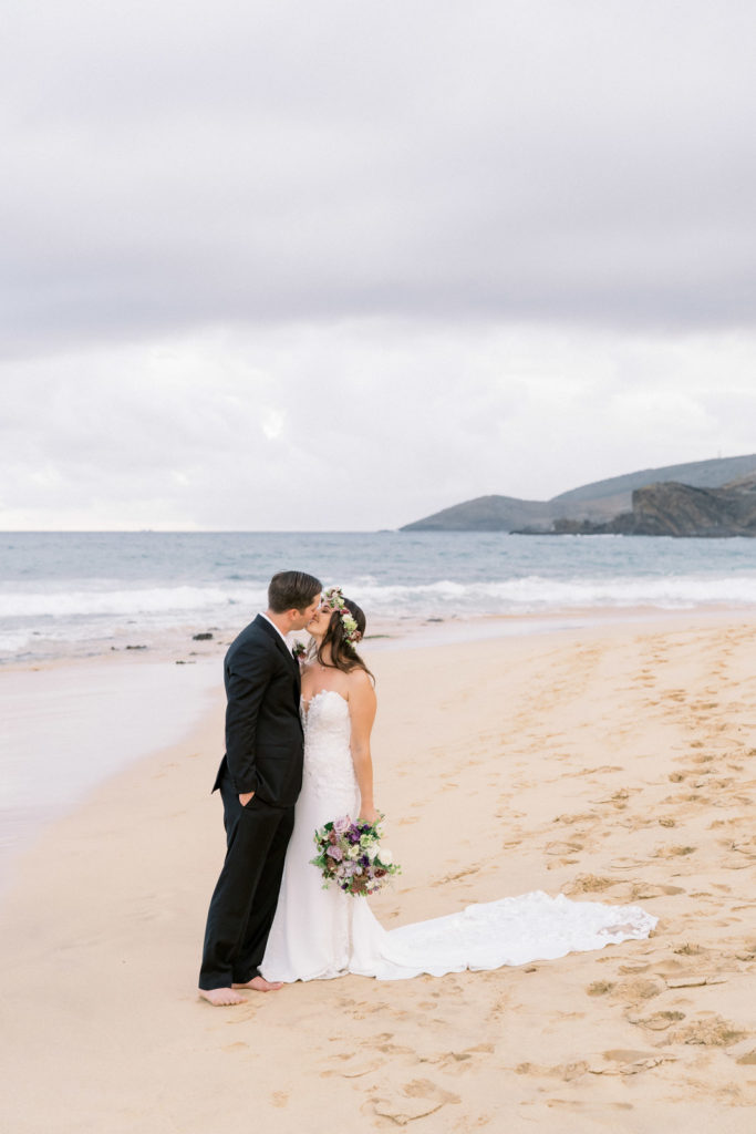 A couple on Sandy Beach on Oahu's south shore. Bride is wearing a beautiful wedding gown and the groom is wearing a black tuxedo.
