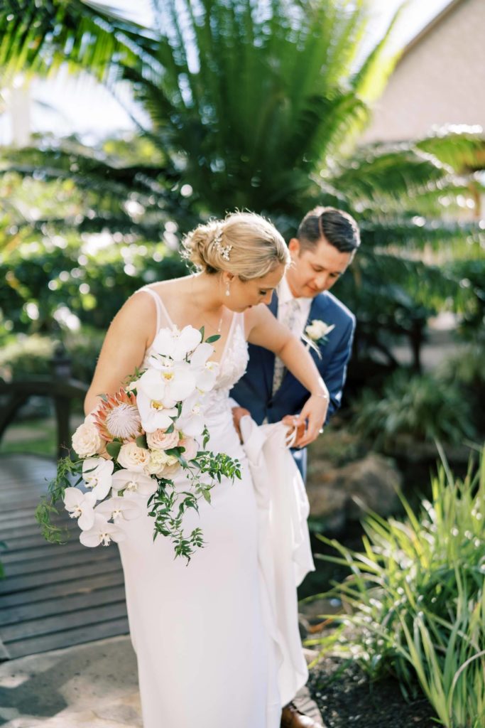 Groom helping the bride carry her dress an intimate elopement in Oahu