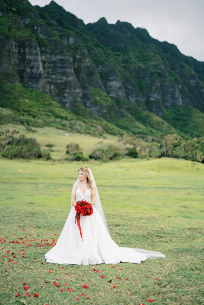 Bride looking away holding red bouquet