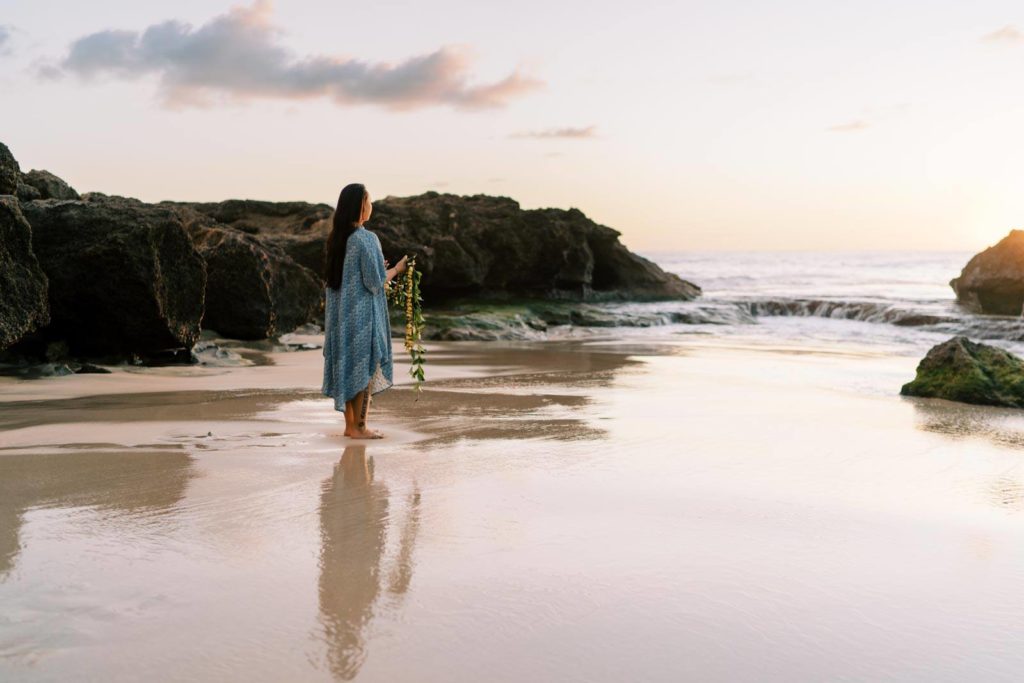 Woman holding a lei walling towards the sunset shore of Waianae beach in Oahu Hawaii Personal branding session
