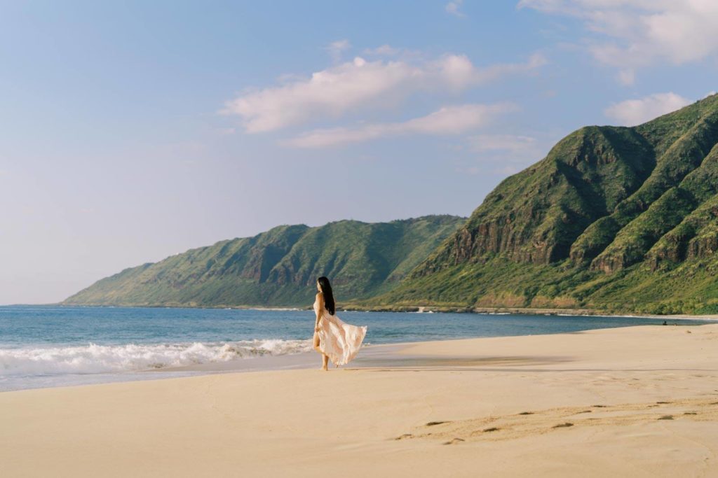 Woman in beautiful maxi dress walking towards the sea in Oahu beach branding session Hawaiian Culture