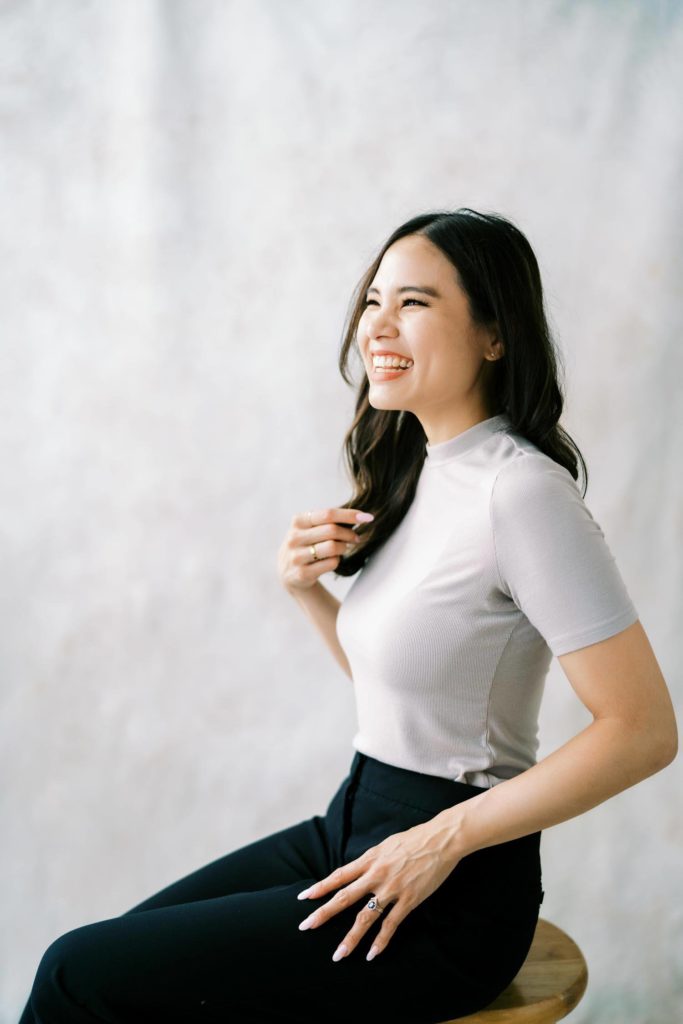 Woman in grey blouse and black trousers smiling joyfully personal branding session