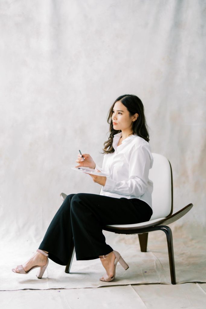 Photo of a Woman in white shirt and black trousers looking away while holding her color palette personal branding session