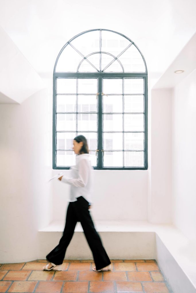 blur effect photo of a woman walking by the vintage european large window holding a color palette
