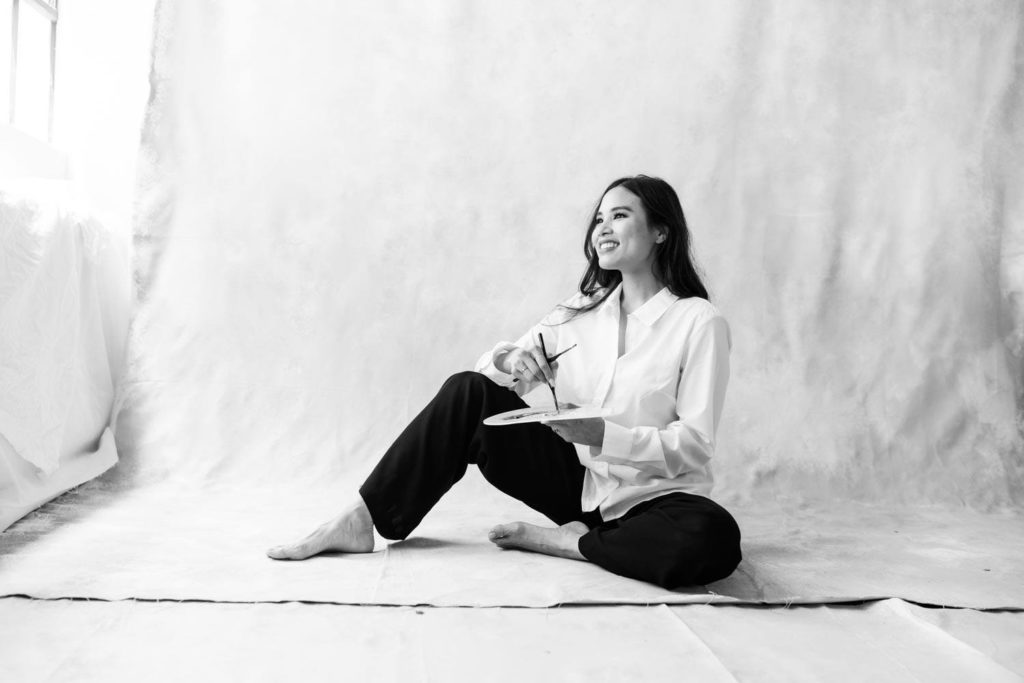 Black and white photo of a woman sitting on the floor and looking to the side happily while holding her color palette a personal branding session with Megan Moura