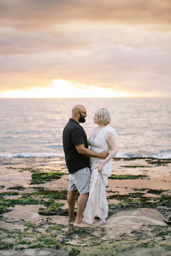 Husband and wife looking at each other's eyes - A dreamy sunset session on the North Shore of Oahu.