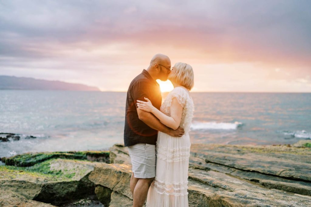Couple kissing with the sunset  in the background, a dreamy sunset session on the North Shore of Oahu.