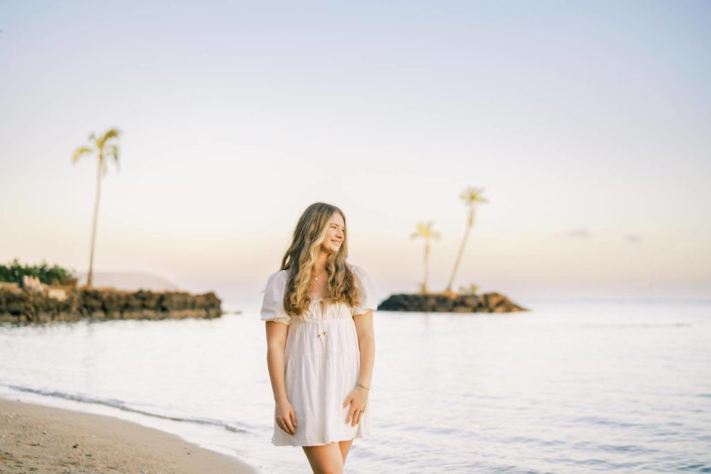 Beautiful young woman in white dress by the beach during sunset
