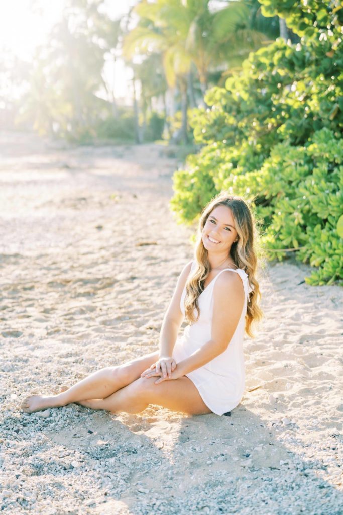Senior student in white dress sitting at the beach