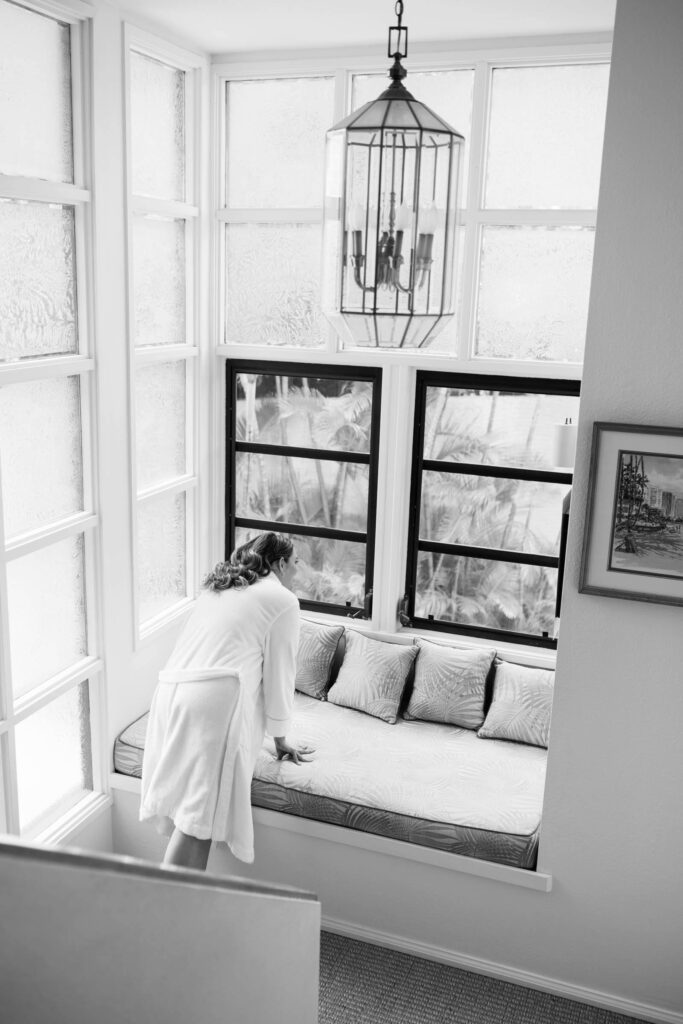 Black and White Photo of a Woman Peeking Out the Window