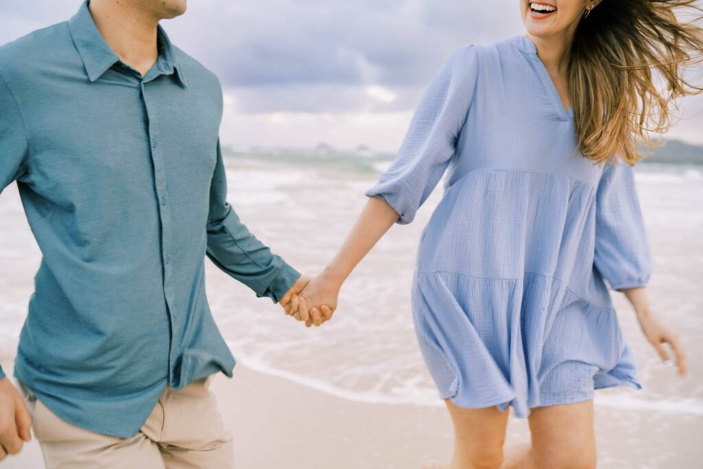 Newly engaged couple holding hands at the beach