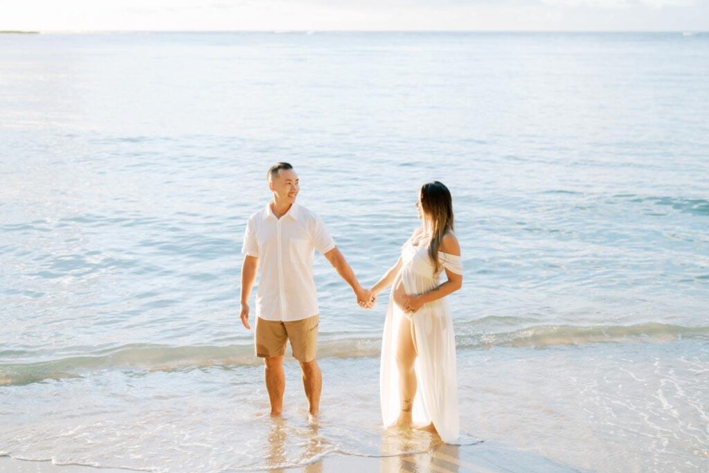 North Shore Maternity Photos of a couple in white holding hands 