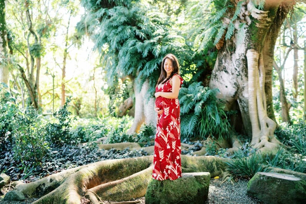 A Pregnant woman smiling vibrantly on her Pregnancy Photo Session at Oahu Botanical Garden