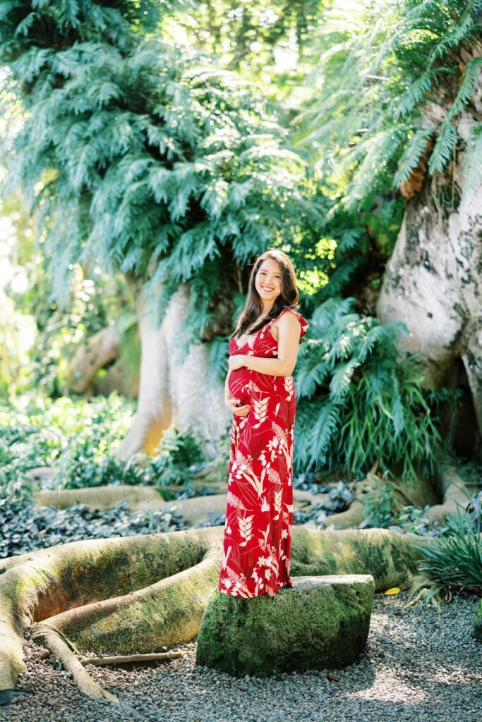 A Pregnant woman smiling vibrantly on her Maternity Photo Session at Oahu Botanical Garden