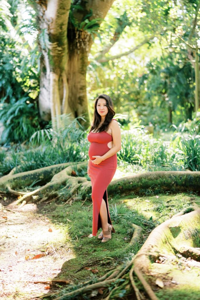 A Pregnant woman wearing a red bodycon dress on her Pregnancy Photo Session at Oahu Botanical Garden