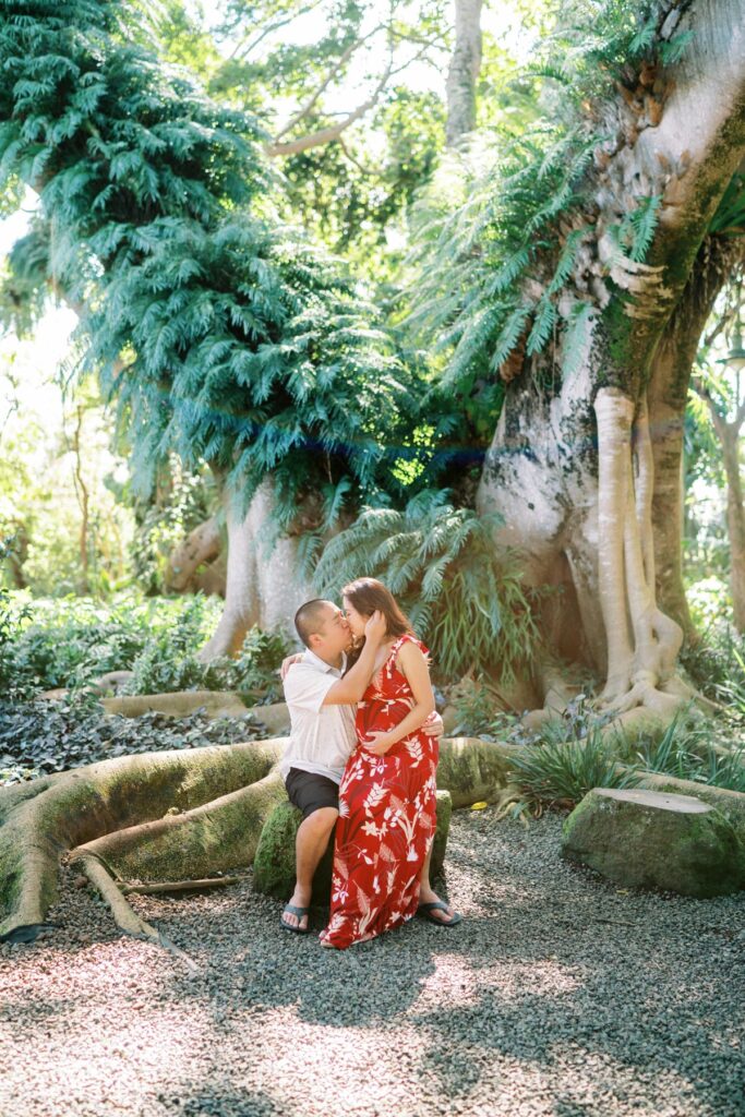 A couple sharing a kiss on their Pregnancy Photo Session at Oahu Botanical Garden