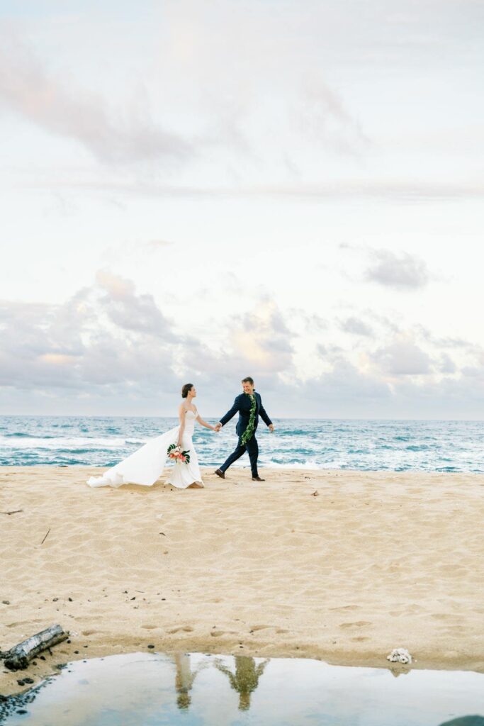 Newlyweds walking at the Na Aina Kai beach Wedding on Kauai